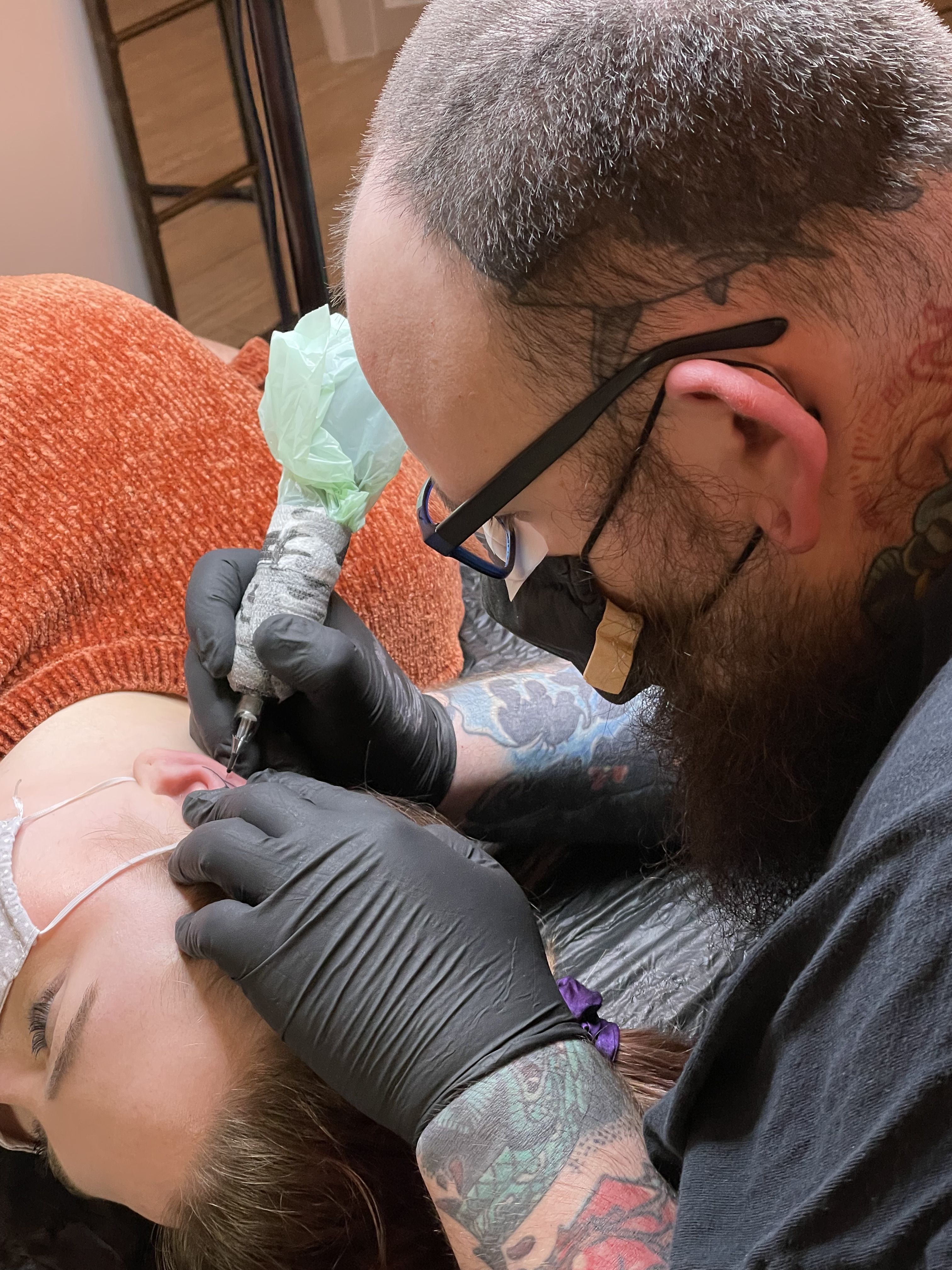 tattoo artist tattooing ear
